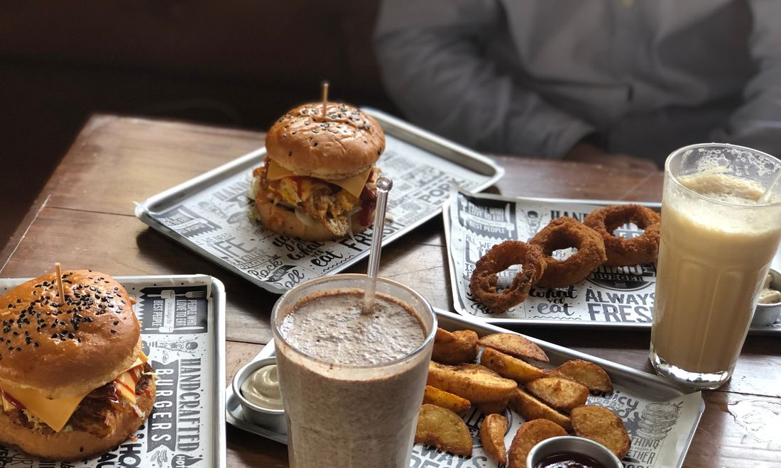 A diner spread of burgers and sides on the table.